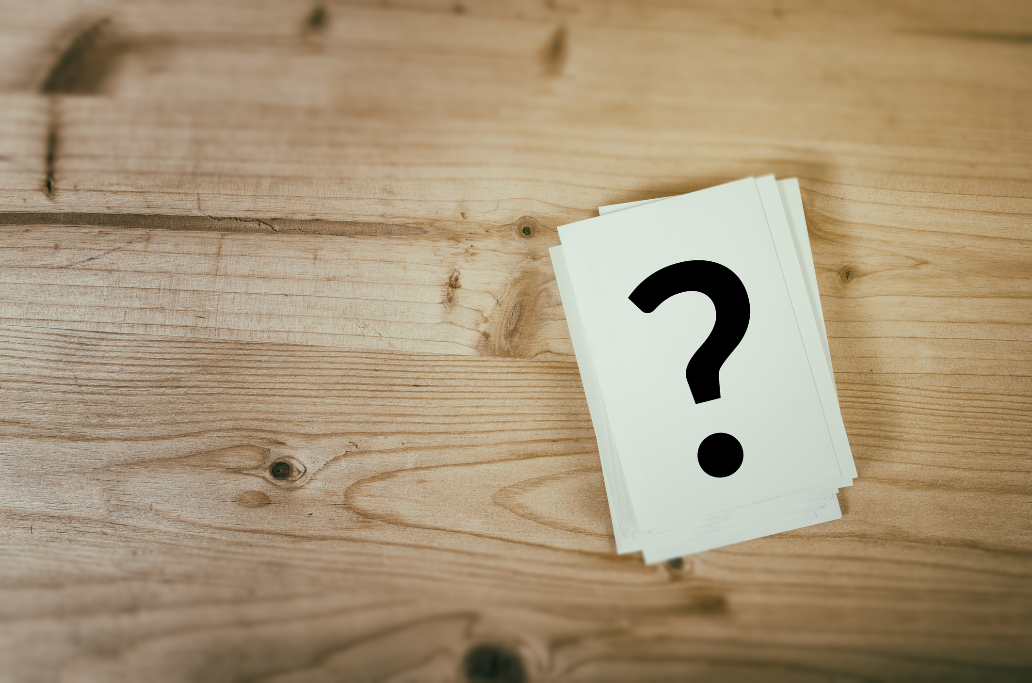 Card with question mark on it on a wooden background