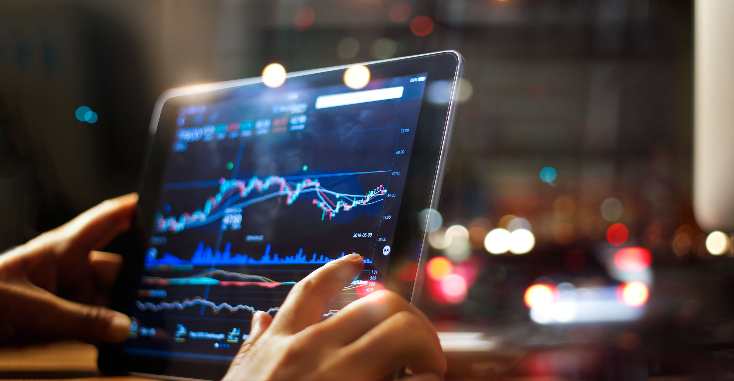 A person holding a computer screen with a stock price chart