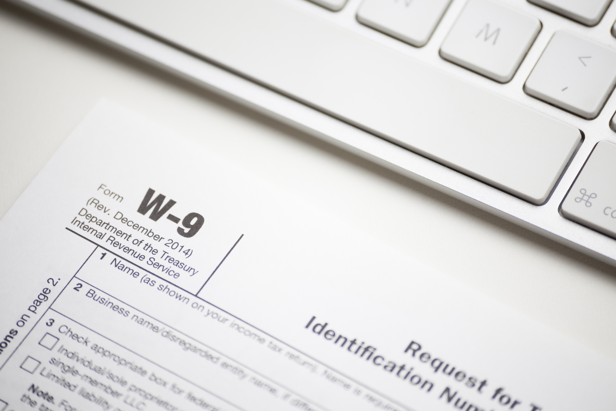 A W-9 form sitting on a desk in front of a keyboard