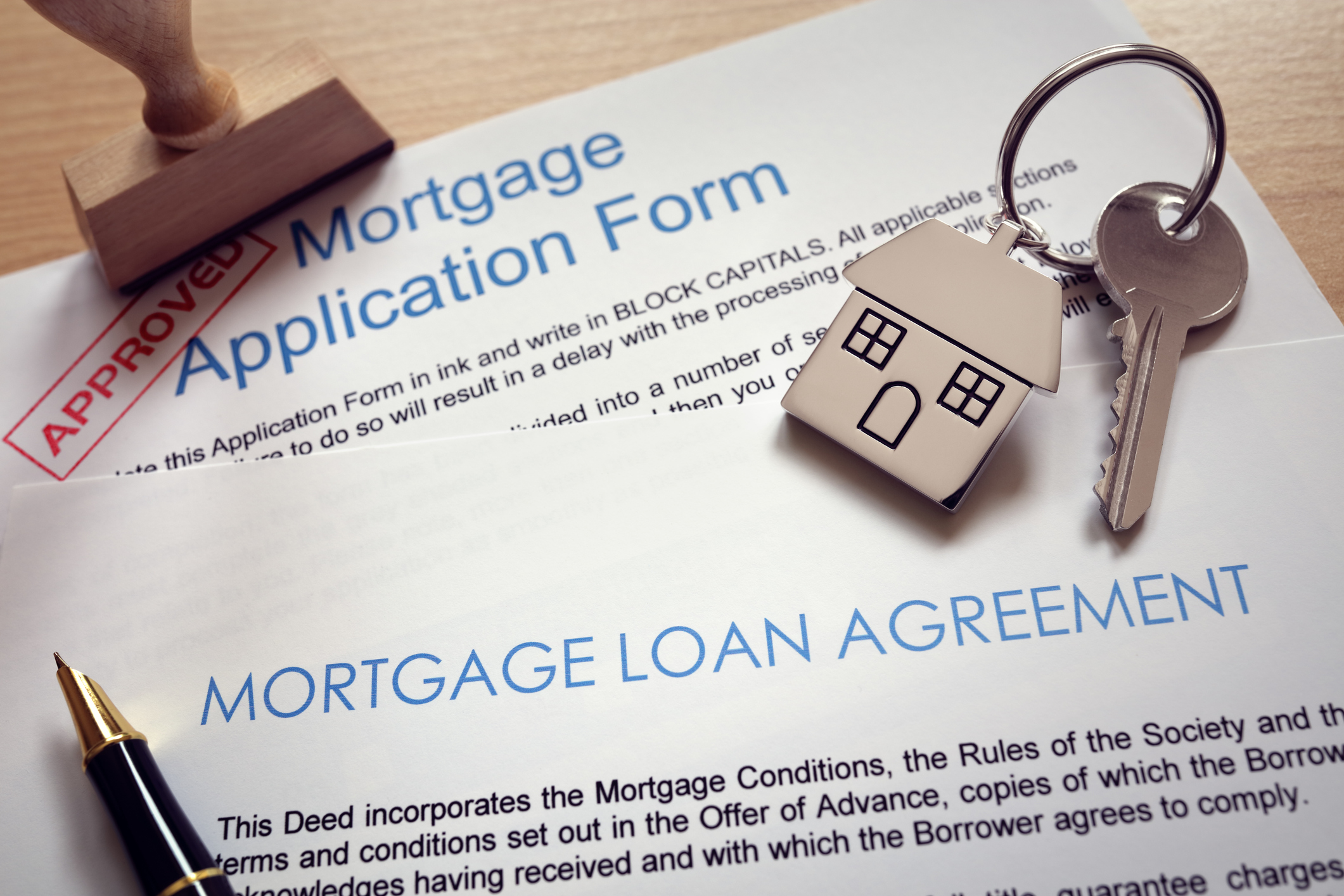 A new house key sitting on top of mortgage loan forms.