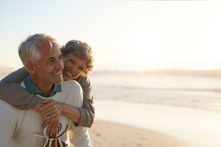An older couple hugging on the beach.