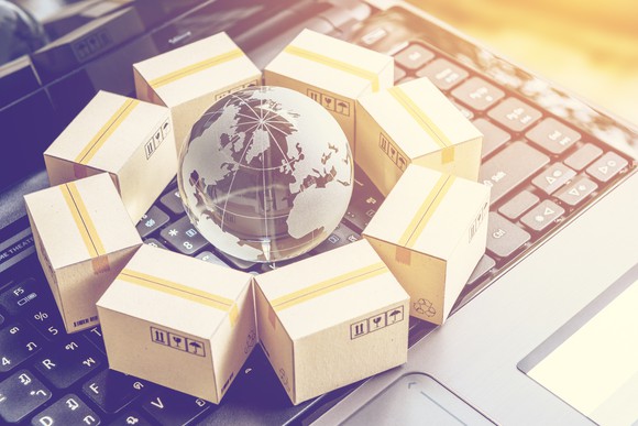 Packages put in circle around a clear crystal globe with world map on a laptop keyboard