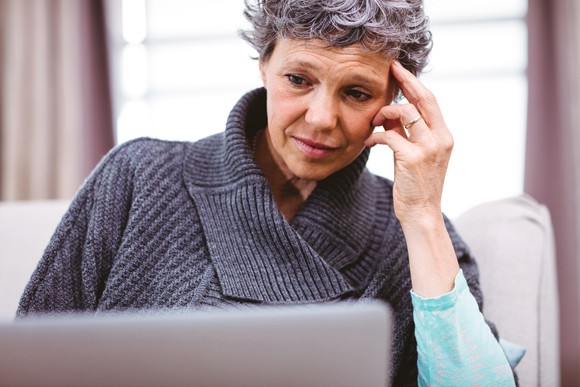 mature woman looking at laptop computer with raised eyebrows and thinking