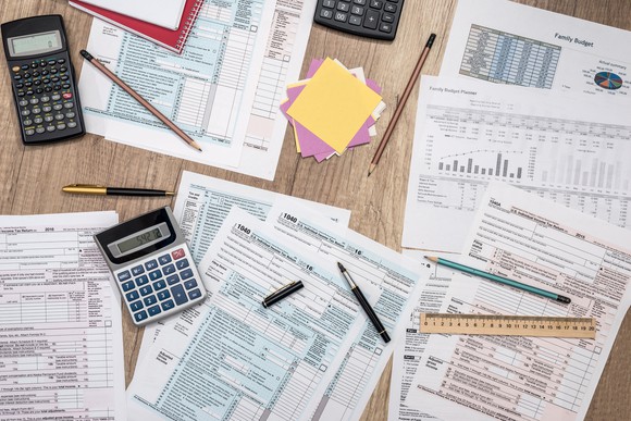 An aerial view of tax documents, calculators, and pencils spread out on a table.
