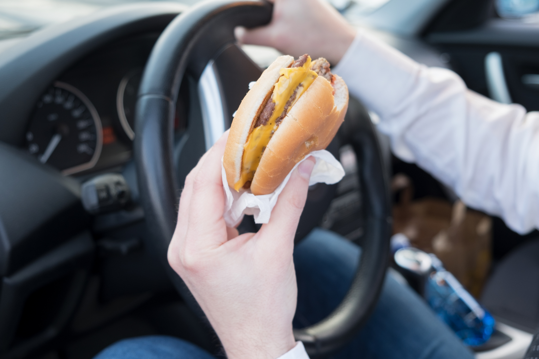 A man eats a burger while driving.