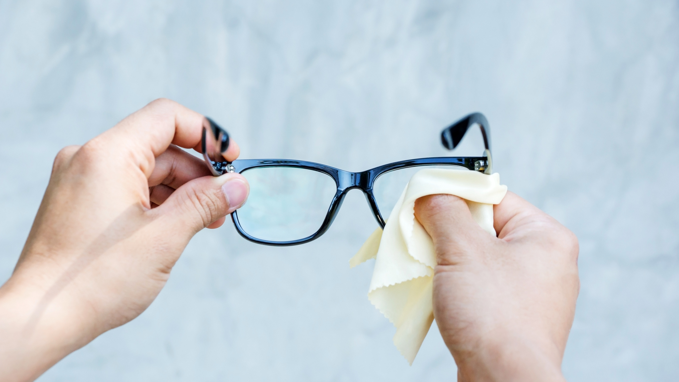 Someone cleaning a pair of eye glasses.