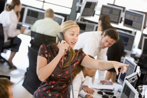 Stock Trader On Phone With Coworkers Getty