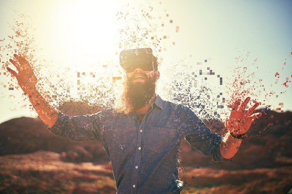 Guy wearing VR headset. He has lots of pixels around his hands.