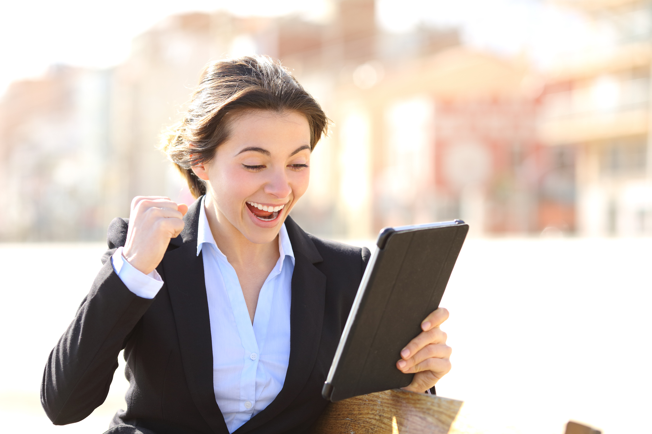 A cheering businesswoman holding a tablet.