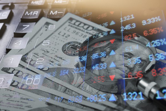 A stack of 100 dollar bills on top of a calculator with a market chart superimposed.