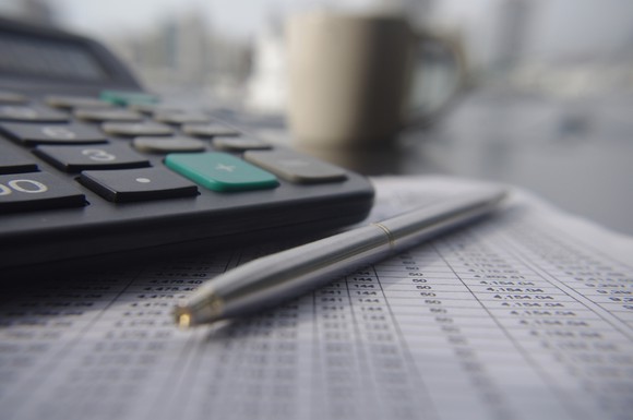 Calculator and pen resting on a financial statement, with a coffee cup in the background