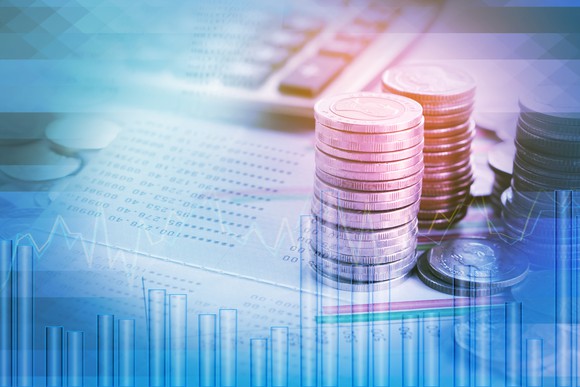 Double exposure of piles of coins on financial documents, a calculator, and a stock chart