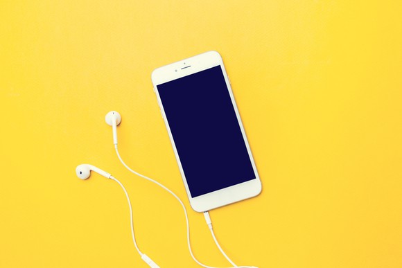 Ear buds plugged in to a mobile phone.