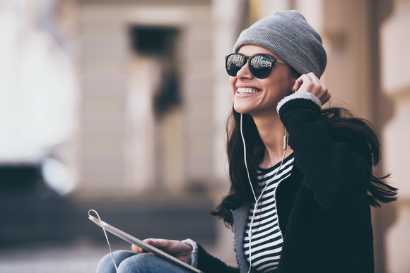 Woman listening to music on tablet via headphones