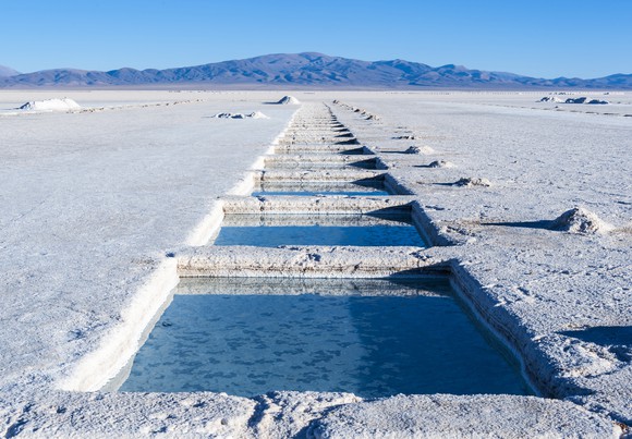 Lithium salt flats with mountain and blue sky in background.