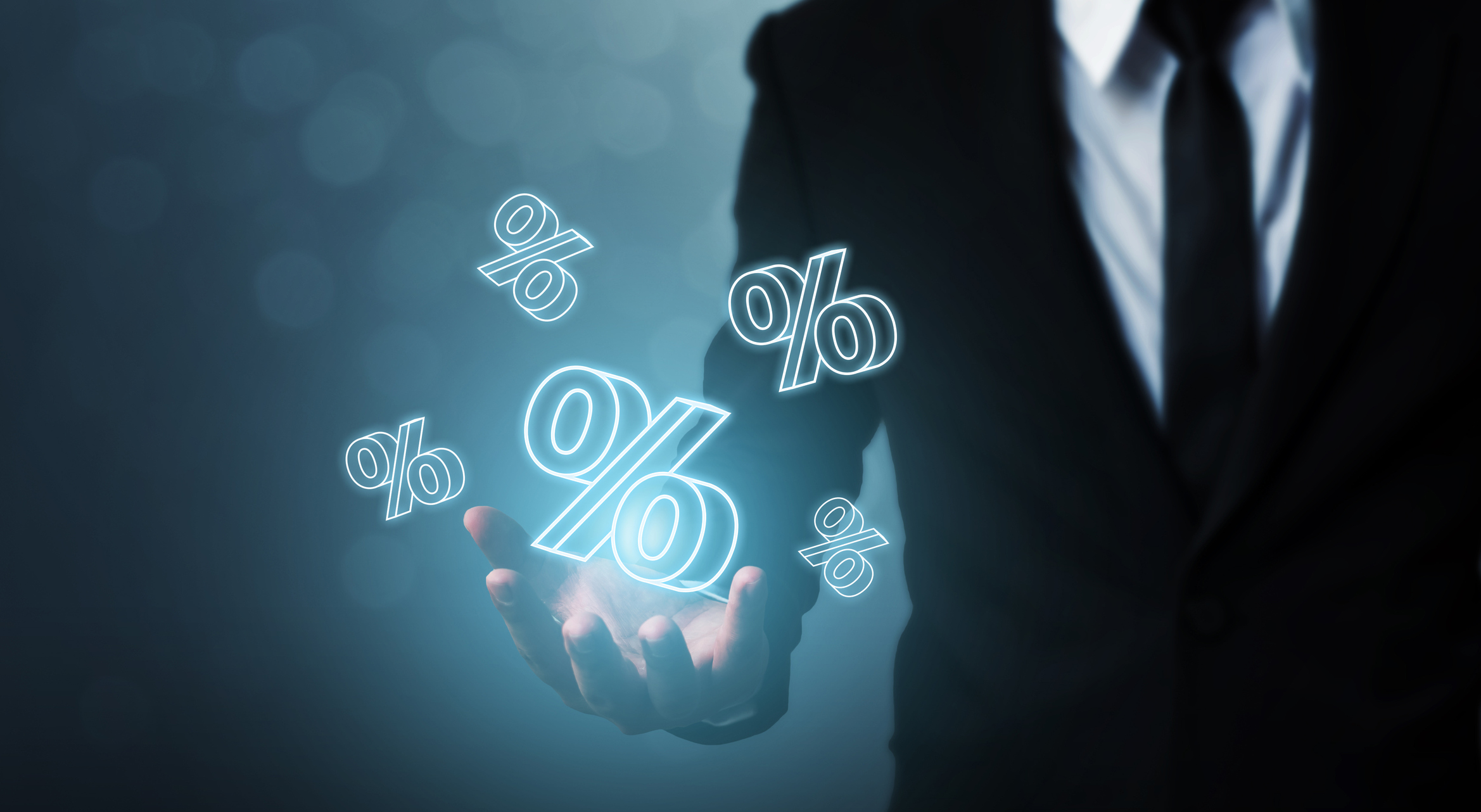 Five 3D percentage symbols hovering above the outstretched hand of a man wearing a suit