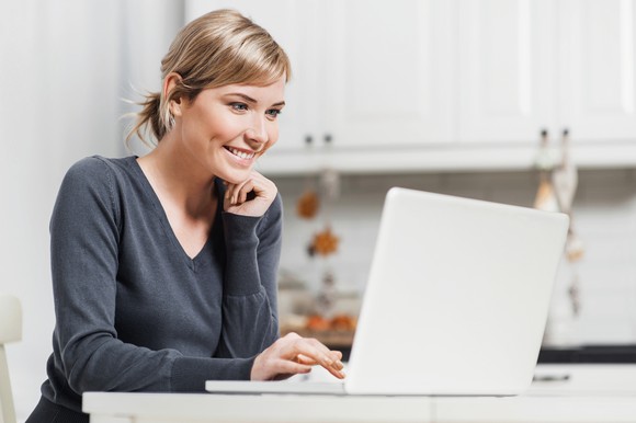 Smiling woman sitting at a table using laptop