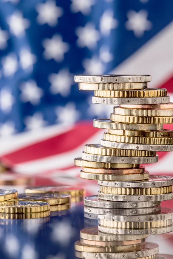 coins piled in front of an Amerian flag