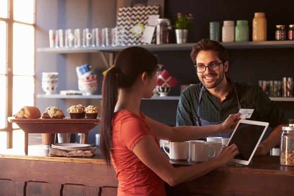 A woman charges a purchase at a coffee shop.