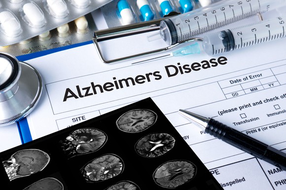 Pad that says Alzheimers Disease surrounded by pills, syringes, a pen, and a stethoscope.