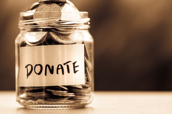 A glass jar full of coins that says Donate.