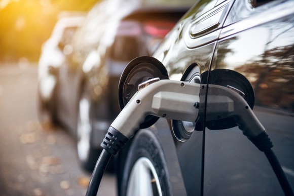 A close-up shot of a an electric car plugged in.