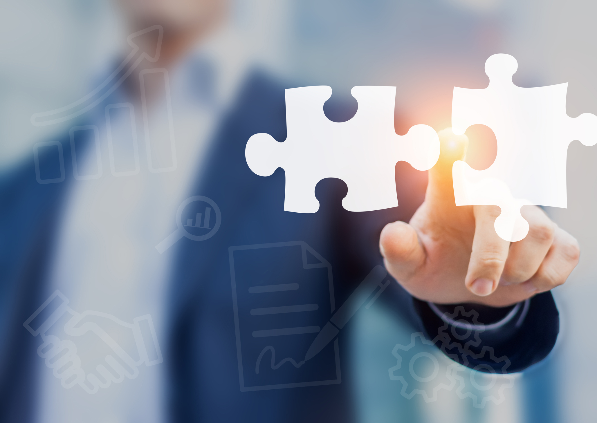 Man in suit pointing to two puzzle pieces about to connect