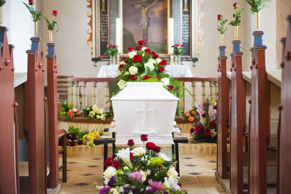 White coffin covered in flowers inside church