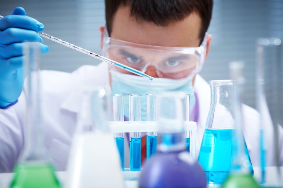 A chemist measuring droplets of liquid into a beaker