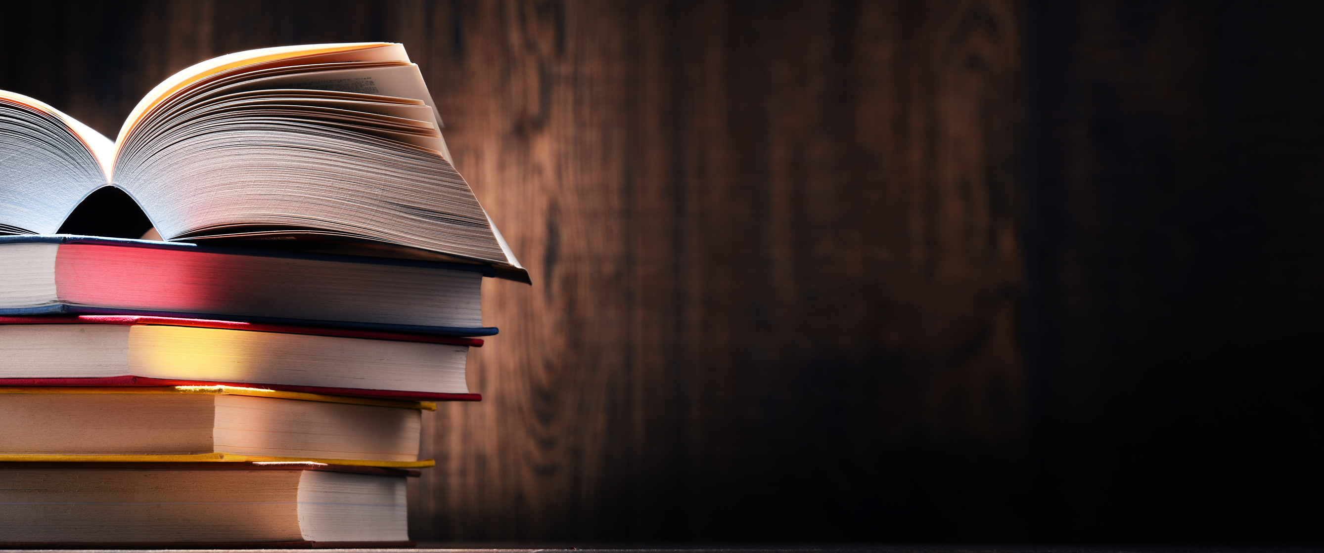 Five books on a table, with the top one open.