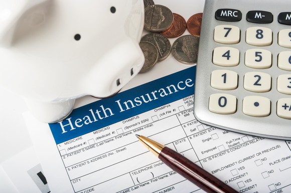 Health insurance enrollment form with calculator and piggy bank.