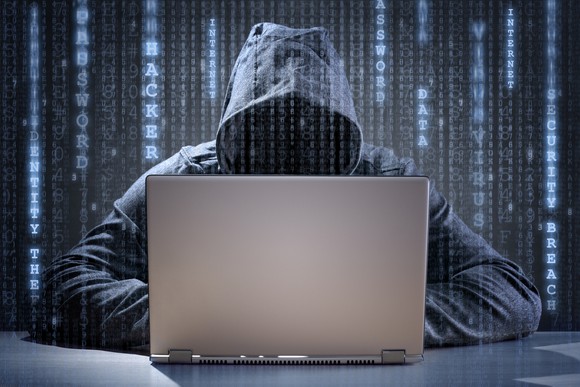 Hooded hacker sitting at a computer.