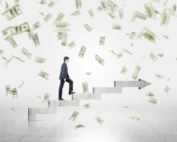 Businessman climbing steps while it rains money