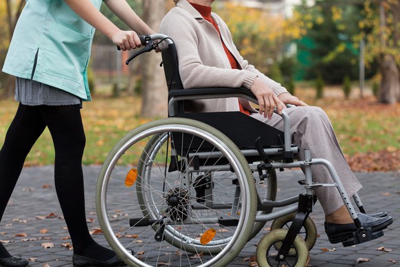 Women in wheelchair being pushed by nurse