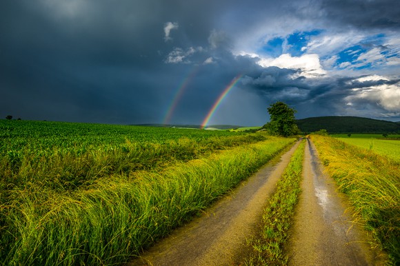 Rural road leading to a rainbow
