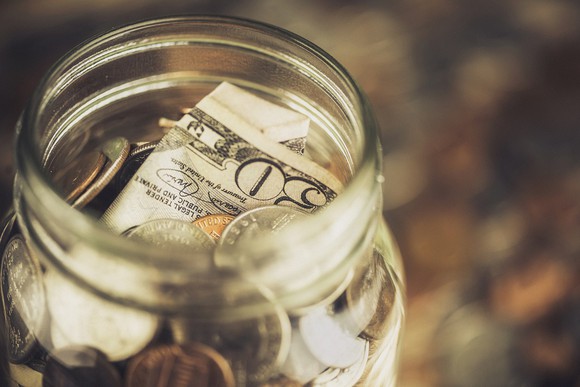 Glass jar filled with coins and currency.