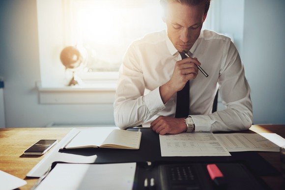 Man seated at a desk, looking over financial statements.