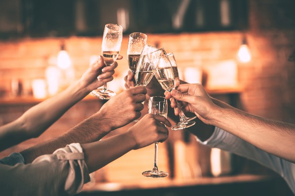 Five people clinking champagne glasses together.