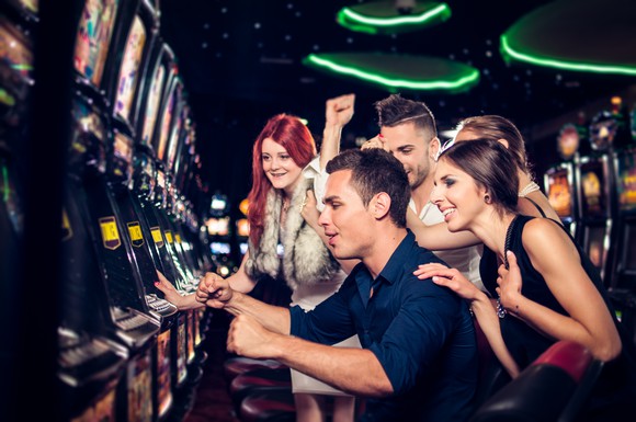Group of young gamblers playing slot machines