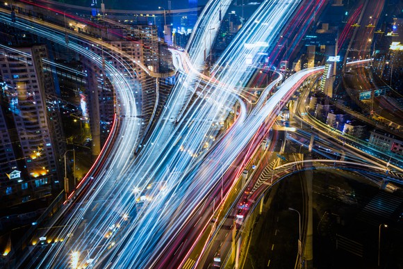 Aerial image of city streets lit up by car lights at night.