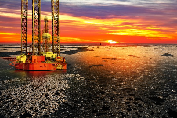 Offshore drilling rig and sunrise over a frozen sea