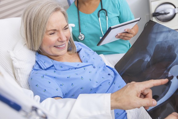 Physician and nurse explaining surgery X-ray to older female patient.