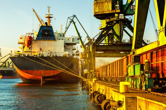 Industrial cargo ship with working crane in port.