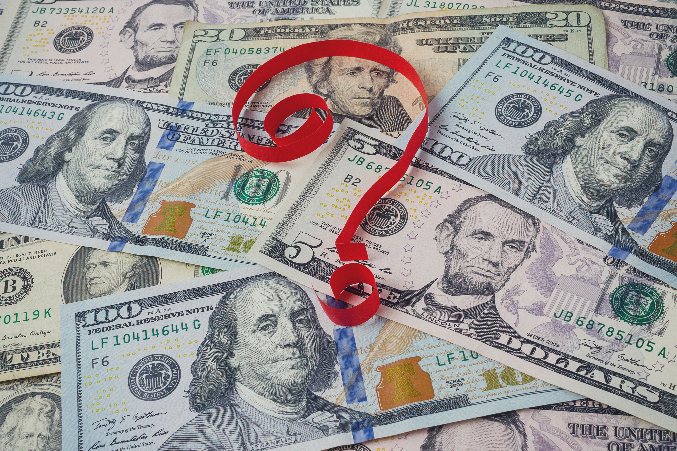 A red question mark sitting on top of a pile of cash.