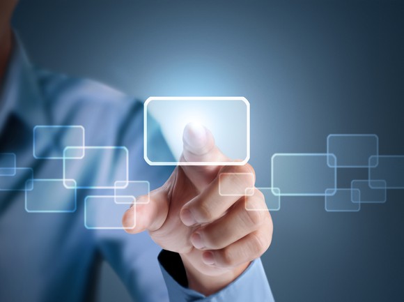 A finger on a transparent touchscreen, pointing toward the reader