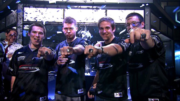 A group of four gamers showing off championship rings from e-sports events.