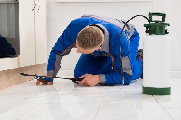 Exterminator treating a house with chemicals.