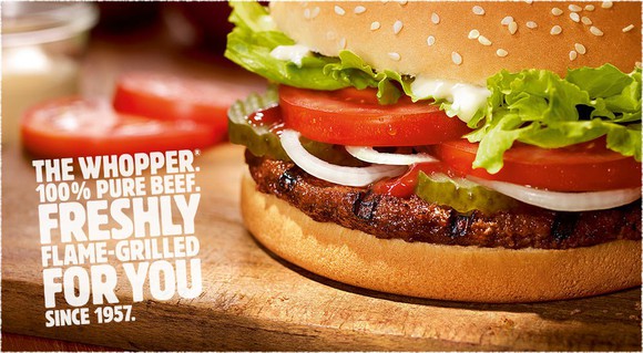 A Burger King Whopper on a cutting board.