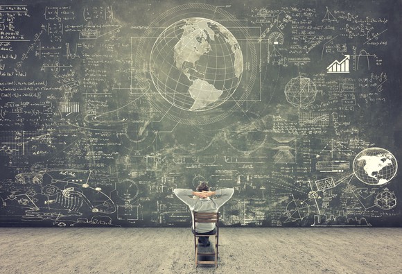 Student sitting in front of a crowded chalkboard.