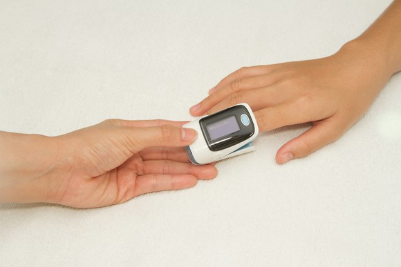 Pulse oximeter on finger with two hands shown
